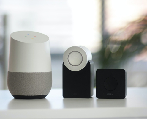 white and gray Google smart speaker and two black speakers