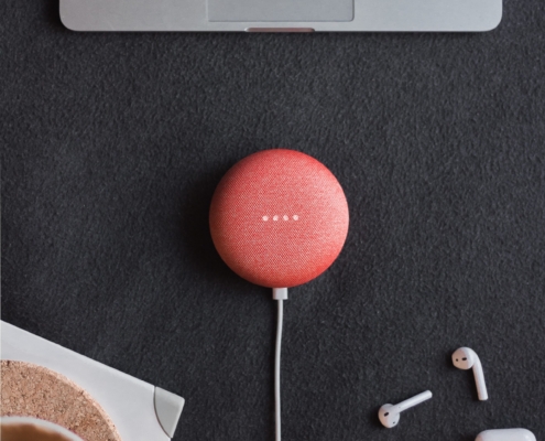 flat lay photography of coral Google Home Mini on black surface beside Apple AirPods